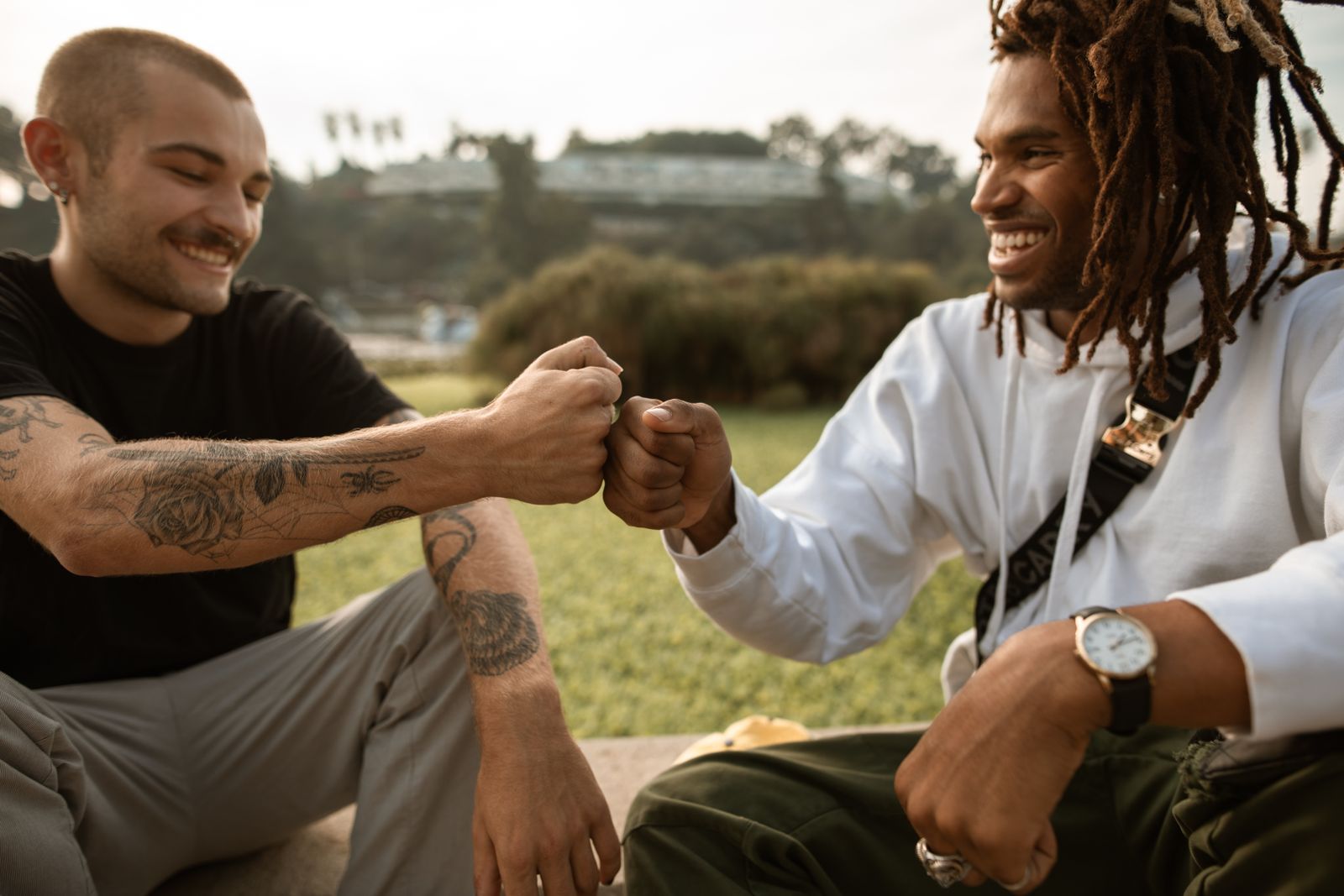 Two people sitting outdoors and greeting each other with a fist bump
